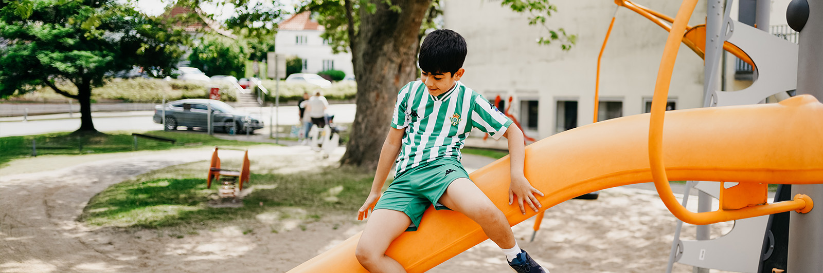 Boy sliding down the slide of en Agito climbing frame.